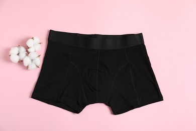 Photo of Comfortable black men's underwear and cotton flowers on pink background, flat lay
