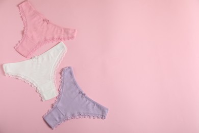 Photo of Women's underwear. Beautiful panties on pink background, flat lay. Space for text