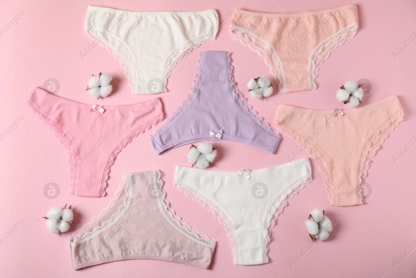 Women's underwear. Beautiful panties and cotton flowers on pink background, flat lay Photo of Women's underwear. Beautiful panties and cotton flowers on pink background, flat lay