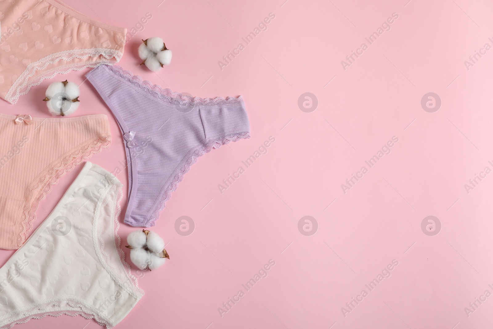 Women's underwear. Beautiful panties and cotton flowers on pink background, flat lay. Space for text Photo of Women's underwear. Beautiful panties and cotton flowers on pink background, flat lay. Space for text