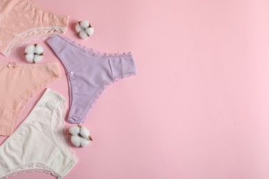 Photo of Women's underwear. Beautiful panties and cotton flowers on pink background, flat lay. Space for text