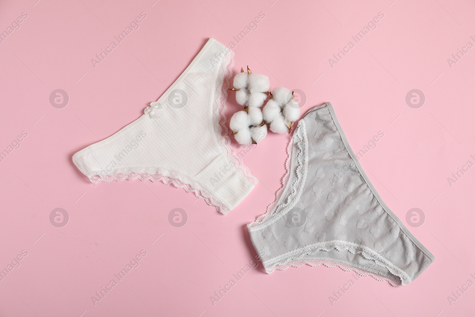 Women's underwear. Beautiful panties and cotton flowers on pink background, flat lay Photo of Women's underwear. Beautiful panties and cotton flowers on pink background, flat lay