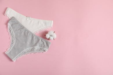 Photo of Women's underwear. Beautiful panties and cotton flower on pink background, flat lay. Space for text