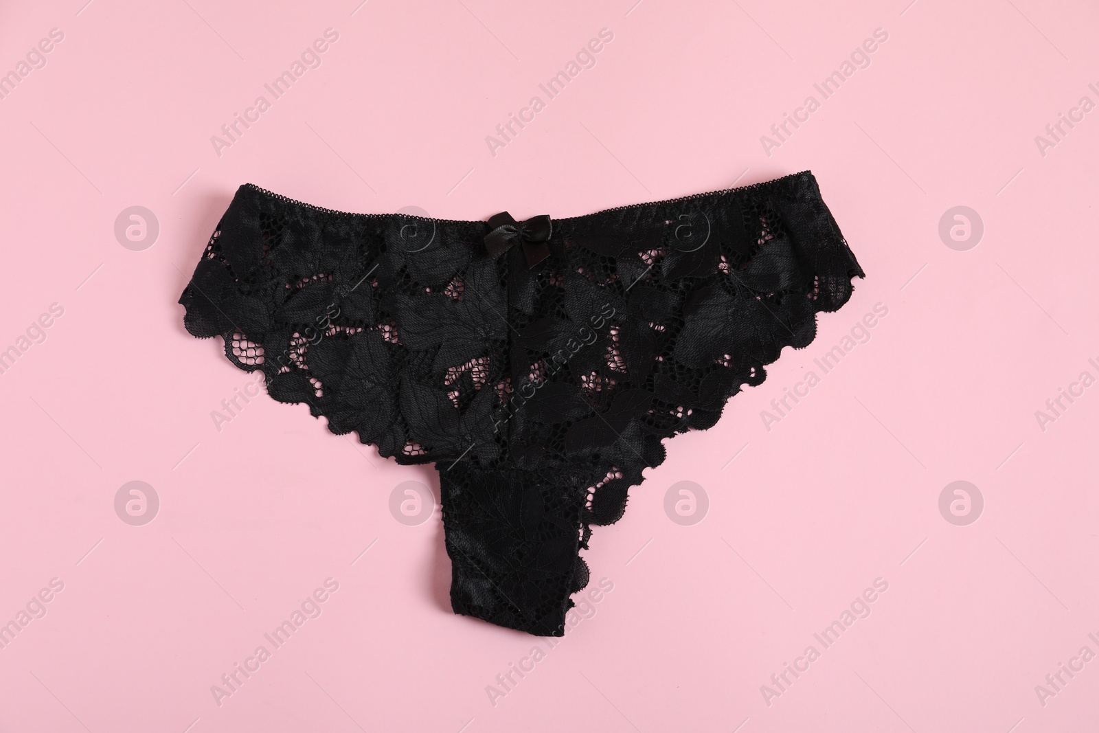 Women's underwear. Beautiful black panties on pink background, top view Photo of Women's underwear. Beautiful black panties on pink background, top view