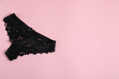 Photo of Women's underwear. Beautiful black panties on pink background, top view. Space for text