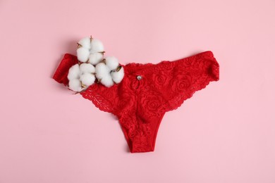 Photo of Women's underwear. Beautiful panties and cotton flowers on pink background, top view