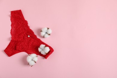 Photo of Women's underwear. Beautiful panties and cotton flowers on pink background, flat lay. Space for text