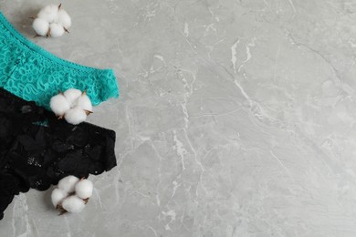 Photo of Women's underwear. Beautiful panties and cotton flowers on gray marble background, flat lay. Space for text