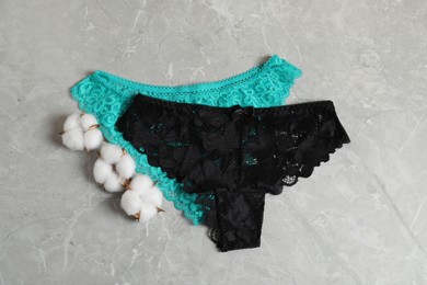 Photo of Women's underwear. Beautiful panties and cotton flowers on gray marble background, flat lay