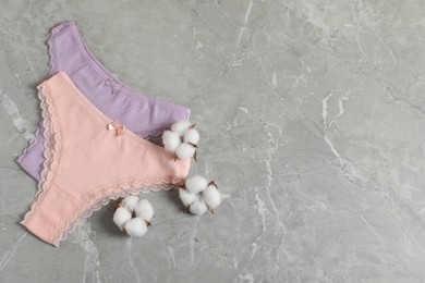 Photo of Women's underwear. Beautiful panties and cotton flowers on gray marble background, flat lay. Space for text