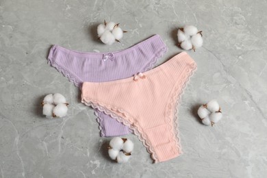Photo of Women's underwear. Beautiful panties and cotton flowers on gray marble background, flat lay