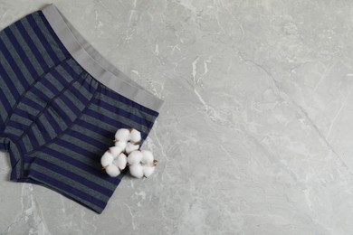 Photo of Comfortable men's underwear and cotton flowers on gray marble background, top view. Space for text
