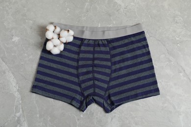 Photo of Comfortable men's underwear and cotton flowers on gray marble background, top view