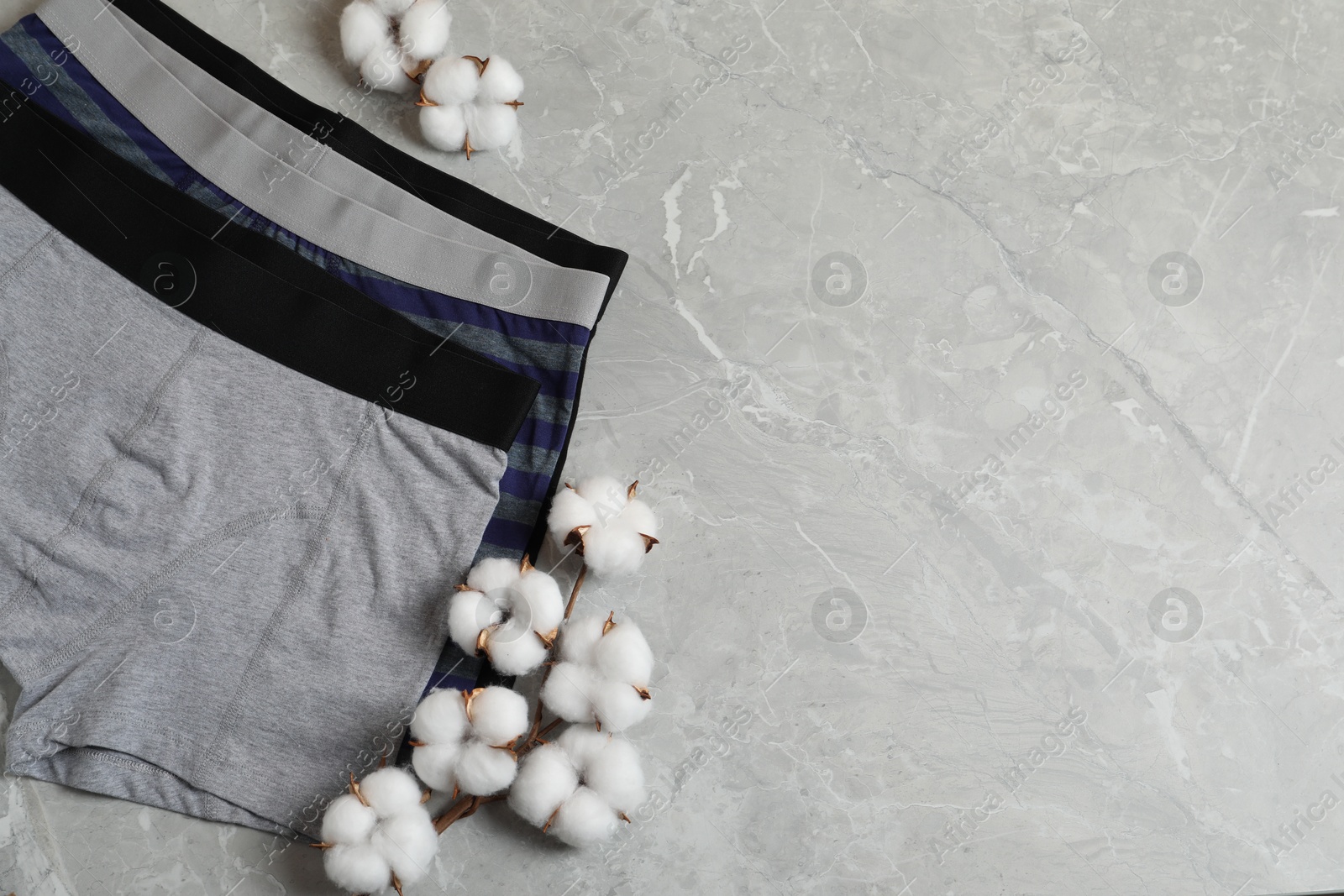 Comfortable men's underwear and cotton flowers on gray marble background, flat lay. Space for text Photo of Comfortable men's underwear and cotton flowers on gray marble background, flat lay. Space for text