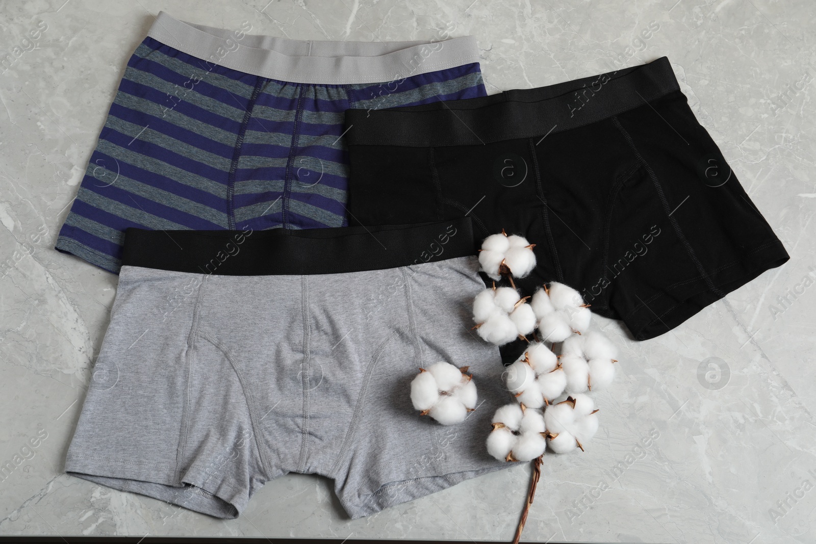 Comfortable men's underwear and cotton flowers on gray marble background, flat lay Photo of Comfortable men's underwear and cotton flowers on gray marble background, flat lay