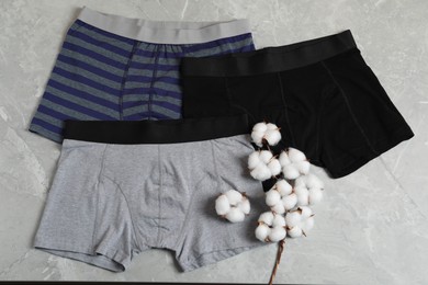 Photo of Comfortable men's underwear and cotton flowers on gray marble background, flat lay