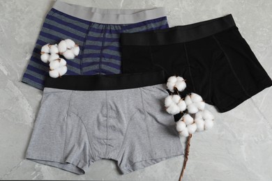Photo of Comfortable men's underwear and cotton flowers on gray marble background, flat lay