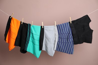 Photo of Comfortable men's underwear on clothes line against light brown background
