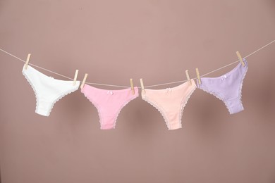 Photo of Women's underwear. Beautiful panties on clothes line against light brown background