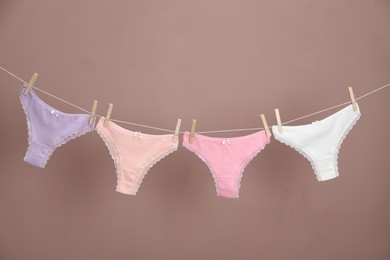 Photo of Women's underwear. Beautiful panties on clothes line against light brown background