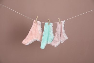 Photo of Women's underwear. Beautiful panties on clothes line against light brown background