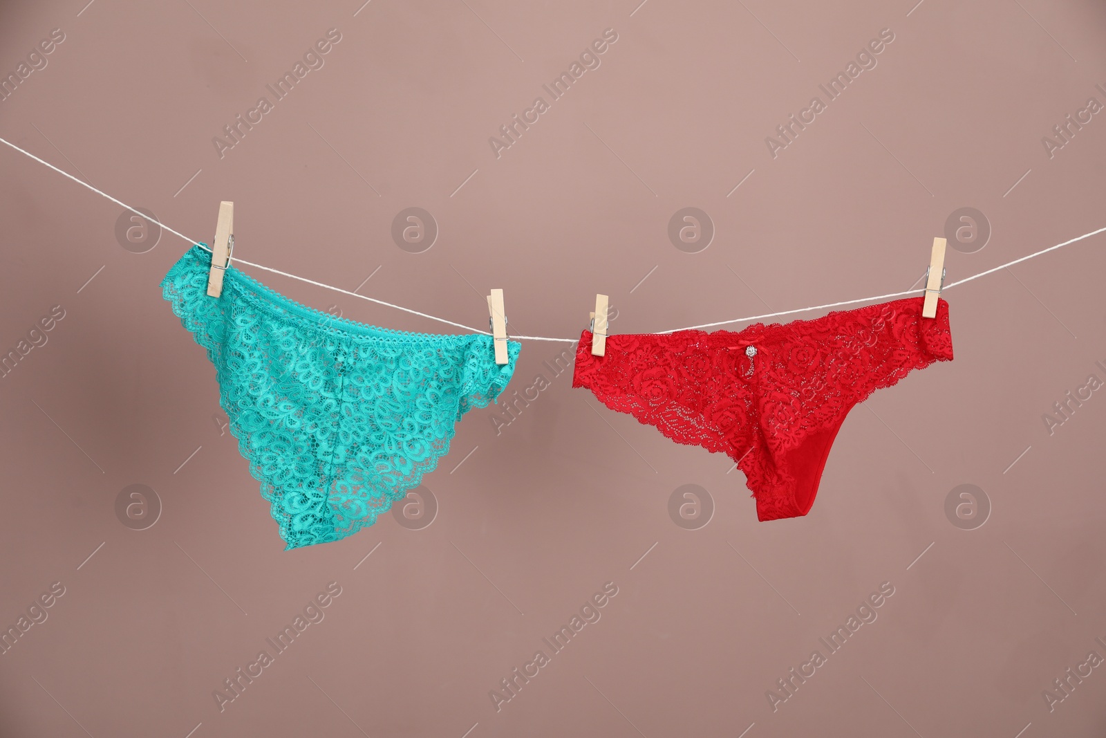 Women's underwear. Beautiful panties on clothes line against light brown background Photo of Women's underwear. Beautiful panties on clothes line against light brown background