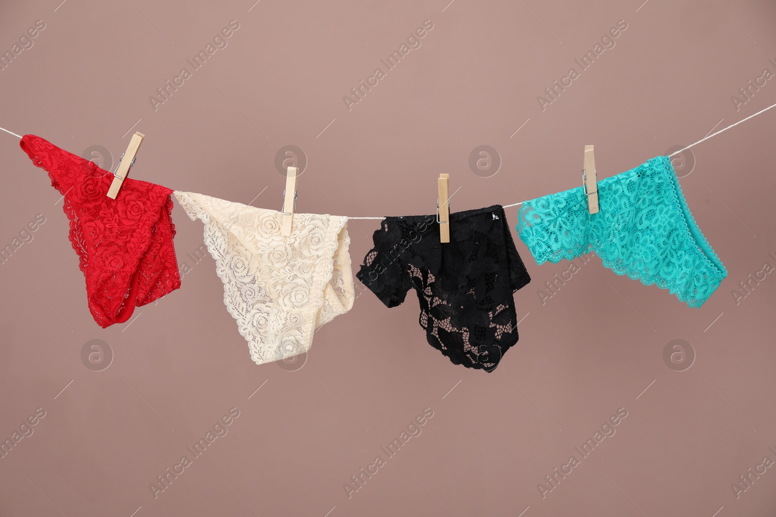 Women's underwear. Beautiful panties on clothes line against light brown background Photo of Women's underwear. Beautiful panties on clothes line against light brown background