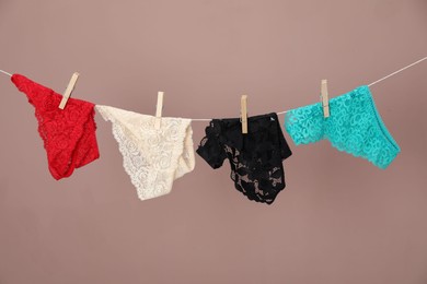 Photo of Women's underwear. Beautiful panties on clothes line against light brown background