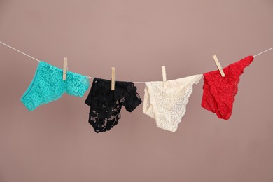 Photo of Women's underwear. Beautiful panties on clothes line against light brown background