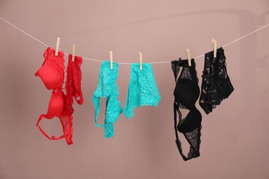 Photo of Women's underwear. Beautiful panties and bras on clothes line against light brown background