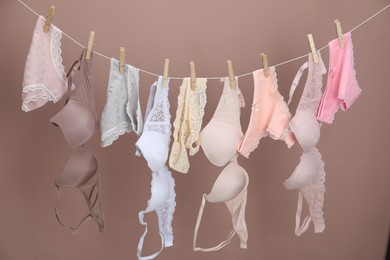 Photo of Women's underwear. Beautiful panties and bras on clothes line against light brown background