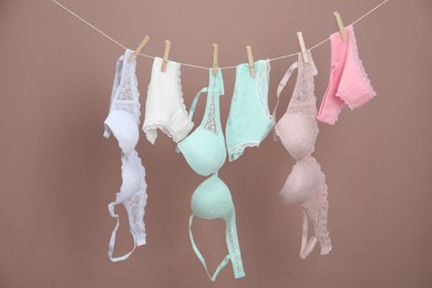 Photo of Women's underwear. Beautiful panties and bras on clothes line against light brown background