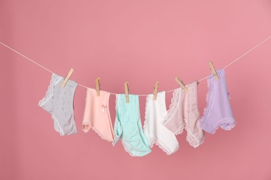 Photo of Women's underwear. Beautiful panties on clothes line against pink background