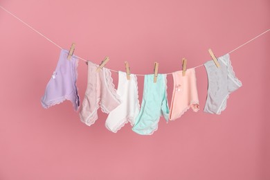 Photo of Women's underwear. Beautiful panties on clothes line against pink background