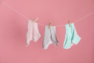 Photo of Women's underwear. Beautiful panties on clothes line against pink background