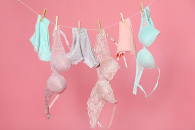Photo of Women's underwear. Beautiful panties and bras on clothes line against pink background