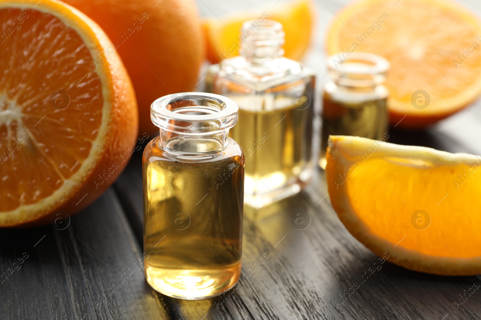 Open perfume bottles with aromatic essential oils and slices of oranges on black wooden table, closeup Photo of Open perfume bottles with aromatic essential oils and slices of oranges on black wooden table, closeup