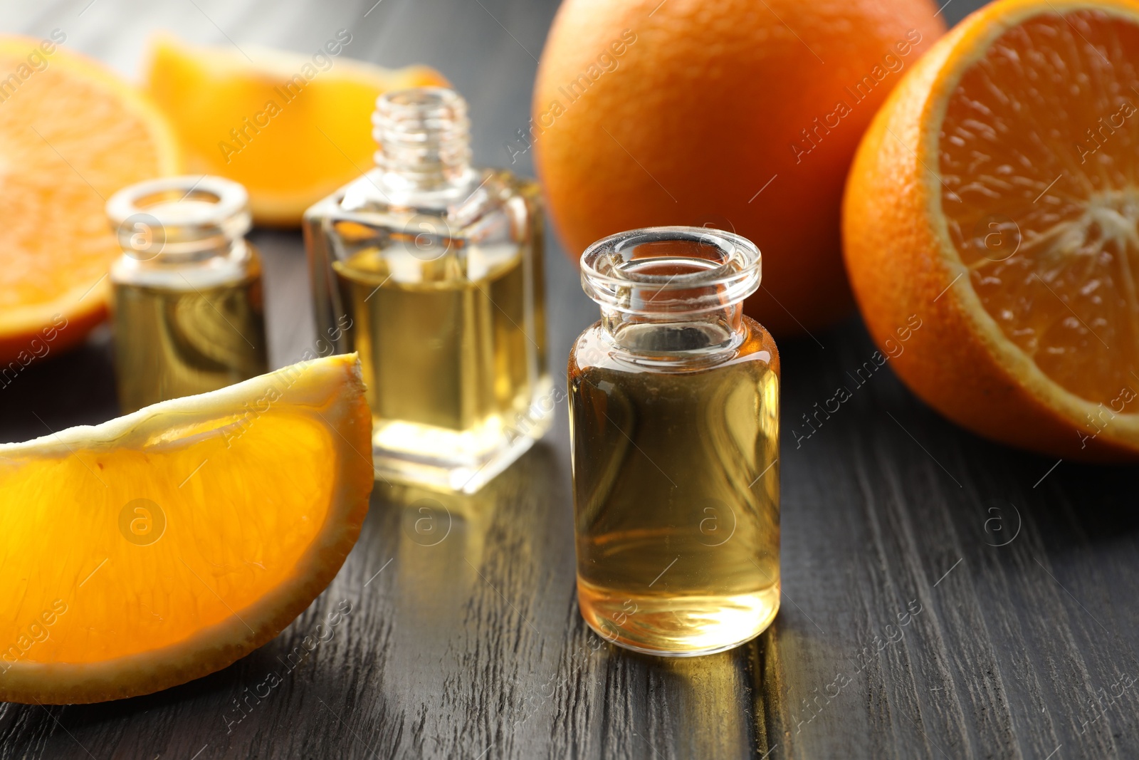 Open perfume bottles with aromatic essential oils and slices of oranges on black wooden table, closeup Photo of Open perfume bottles with aromatic essential oils and slices of oranges on black wooden table, closeup