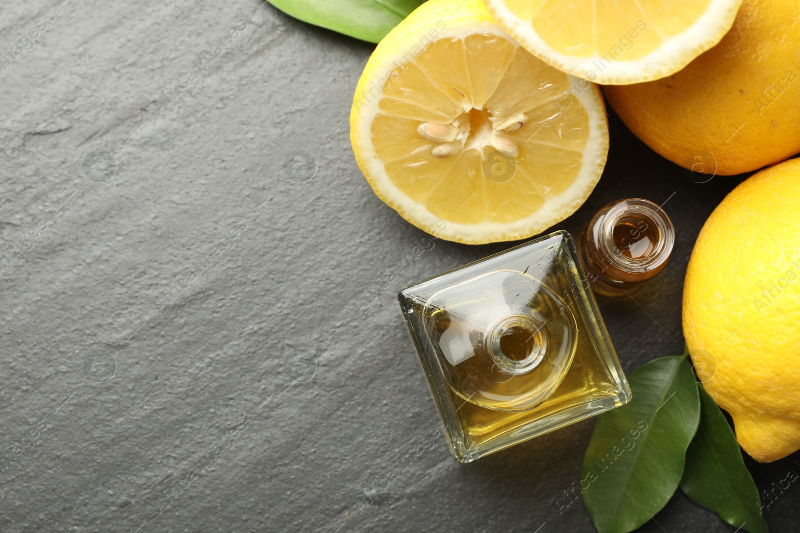 Open perfume bottles with aromatic essential oils, leaves and lemons on dark textured table, flat lay. Space for text Photo of Open perfume bottles with aromatic essential oils, leaves and lemons on dark textured table, flat lay. Space for text