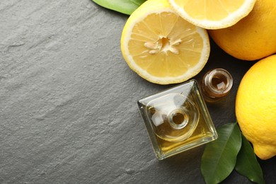Photo of Open perfume bottles with aromatic essential oils, leaves and lemons on dark textured table, flat lay. Space for text