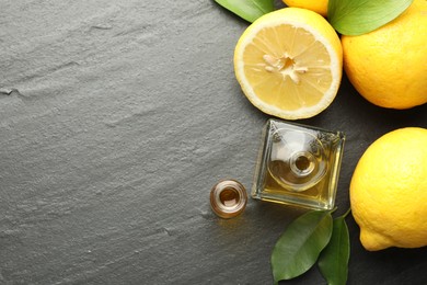 Photo of Open perfume bottles with aromatic essential oils, leaves and lemons on dark textured table, flat lay. Space for text
