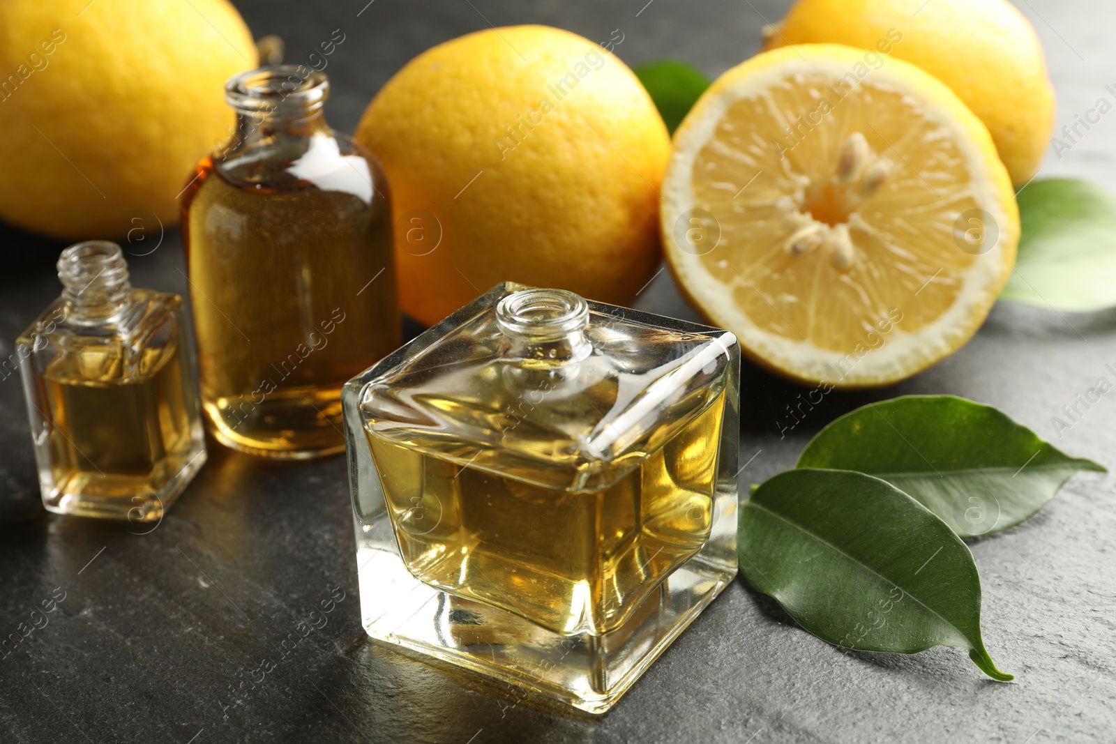 Open perfume bottles with aromatic essential oils, leaves and lemons on dark textured table, closeup Photo of Open perfume bottles with aromatic essential oils, leaves and lemons on dark textured table, closeup