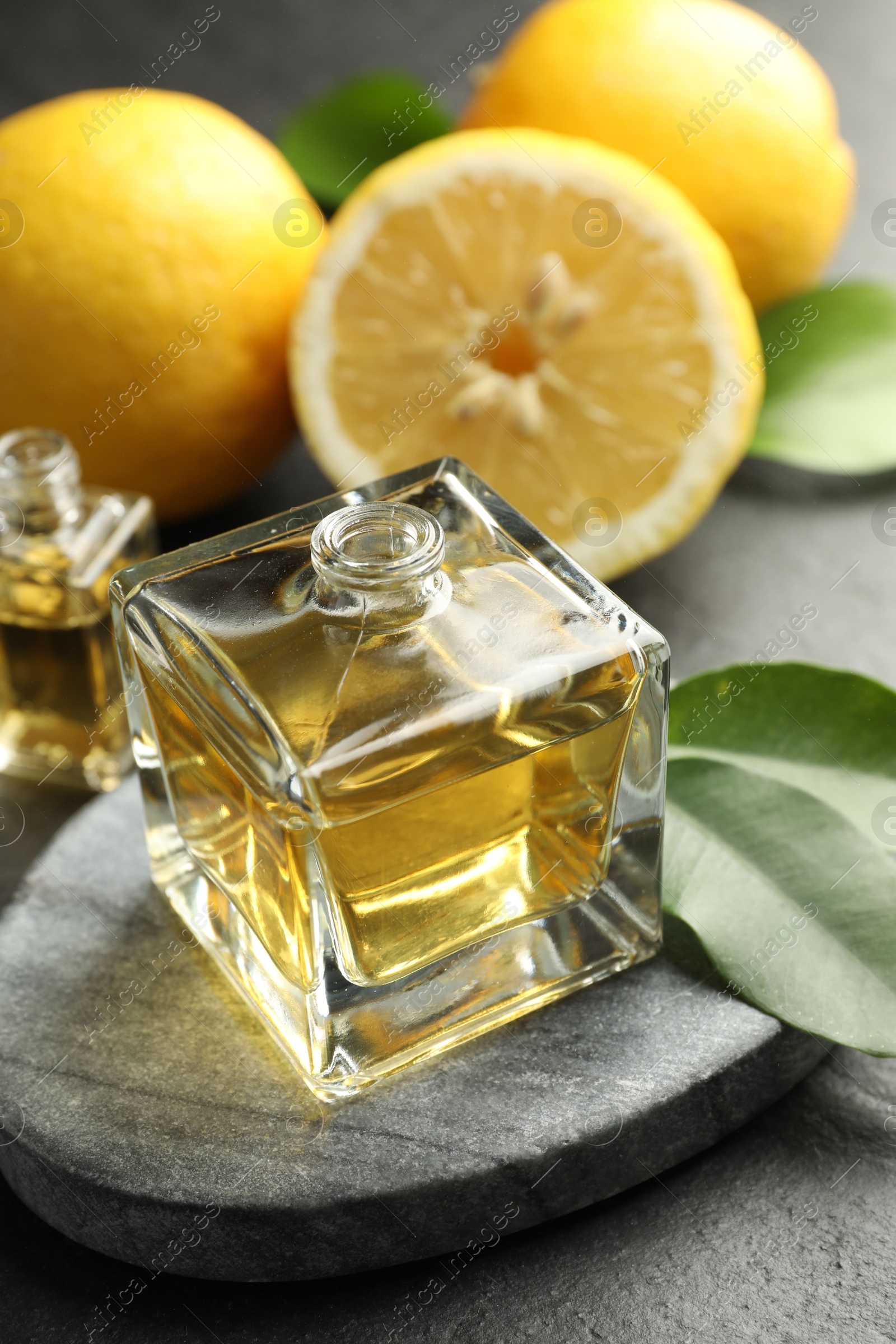 Open perfume bottles with aromatic essential oils, leaves and lemons on dark textured table, closeup Photo of Open perfume bottles with aromatic essential oils, leaves and lemons on dark textured table, closeup
