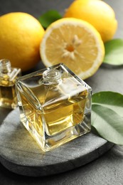 Photo of Open perfume bottles with aromatic essential oils, leaves and lemons on dark textured table, closeup