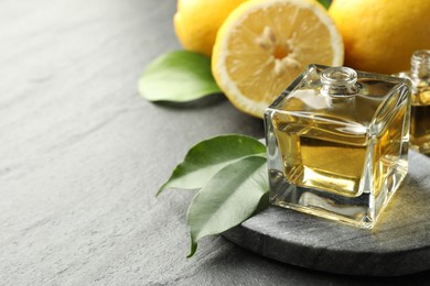 Photo of Open perfume bottle with aromatic essential oil, leaves and lemons on dark textured table, closeup. Space for text