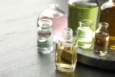 Photo of Open perfume bottles with aromatic essential oils on dark textured table, closeup