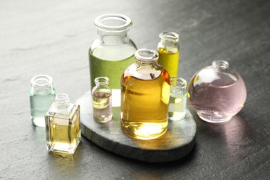 Photo of Open perfume bottles with aromatic essential oils on dark textured table, closeup