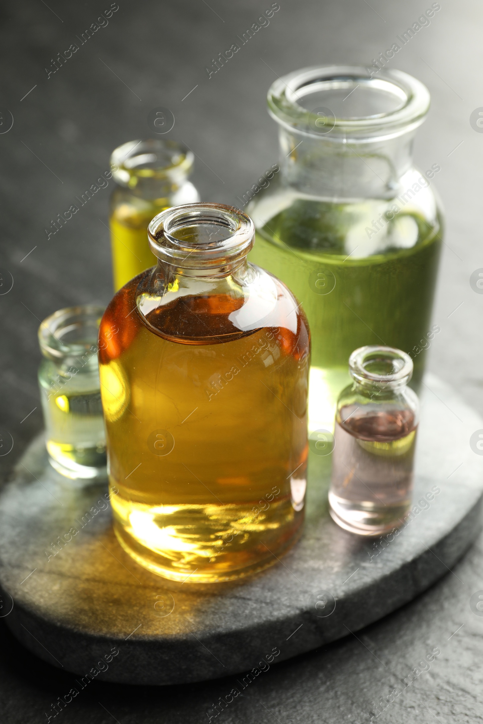 Photo of Open perfume bottles with aromatic essential oils on dark textured table, closeup