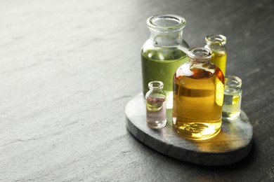 Photo of Open perfume bottles with aromatic essential oils on dark textured table, closeup. Space for text