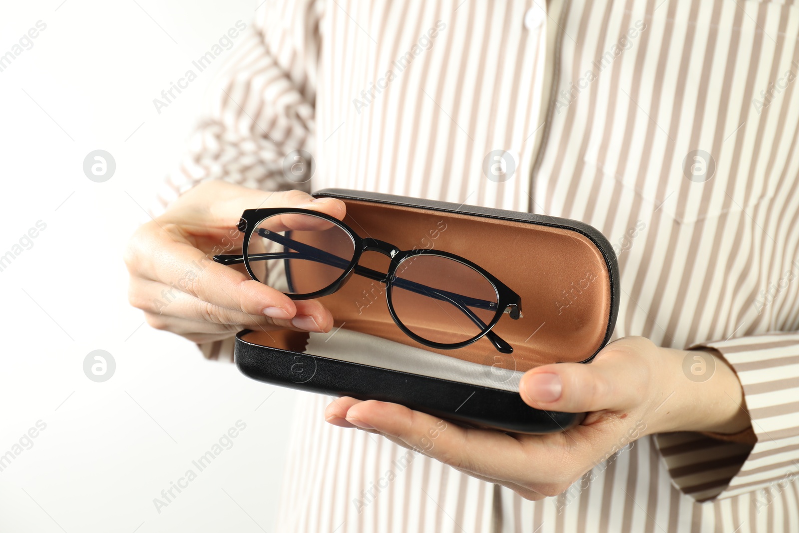 Woman holding case with stylish glasses and cleaning cloth on light background, closeup Photo of Woman holding case with stylish glasses and cleaning cloth on light background, closeup